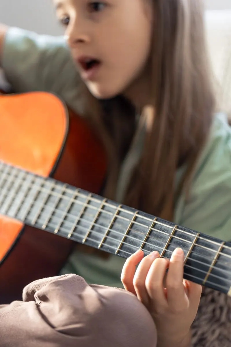 Dziecko gra na gitarze podczas indywidualnych zajęć